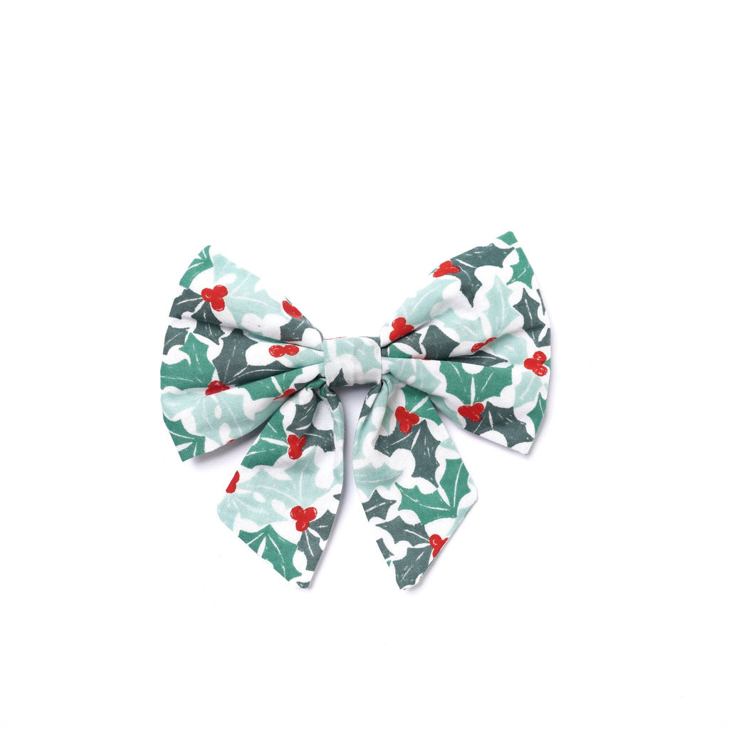 Christmas-themed bow with holly design on a white background