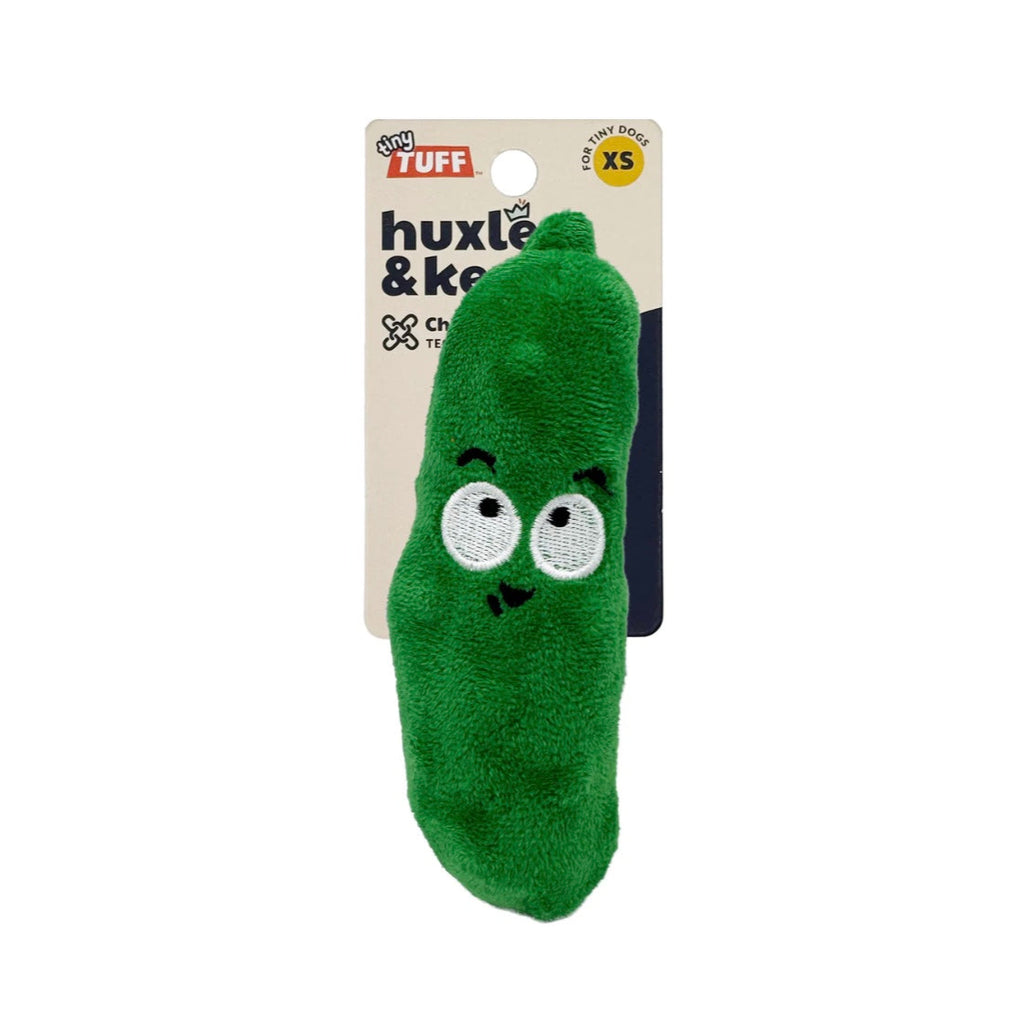 Green pickle-shaped toy with face design on a white background, branded 'huxle & keeple'.