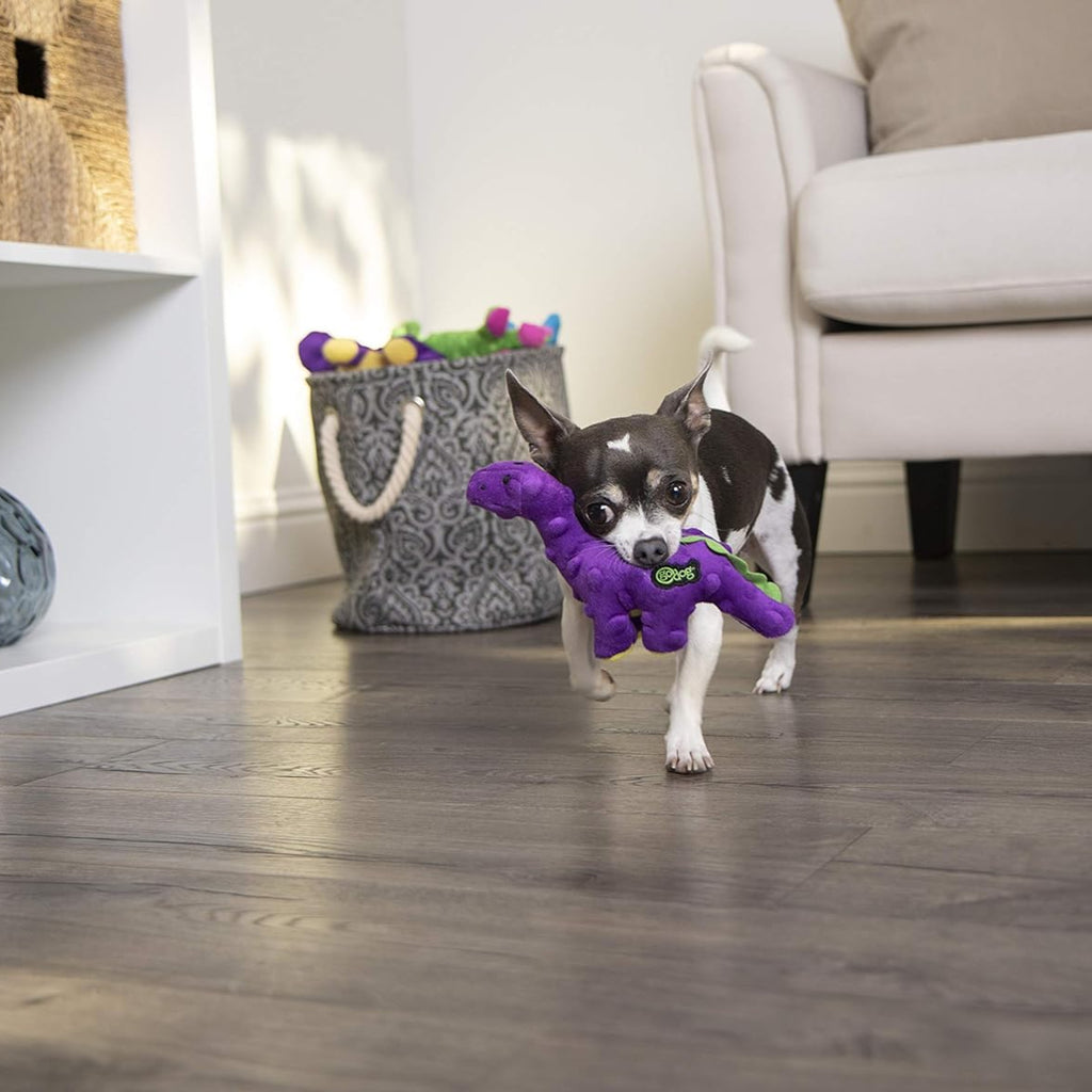 Dog playing with a purple toy on a wooden floor in a living room.